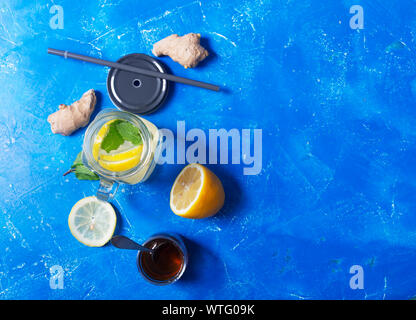 Ingwer Wasser im Glas Glas mit Zitrone und Honig auf einem blauen Hintergrund mit Kopie Raum Stockfoto