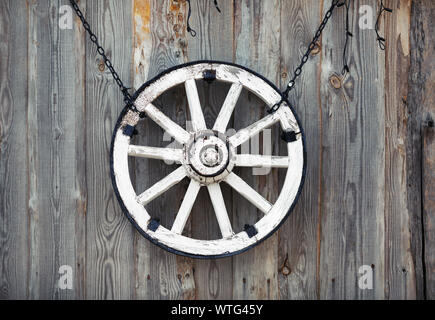 Alte Karre Rad hängen an vintage Holzwand. Stockfoto
