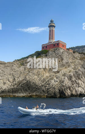 Insel Capri, Italien - AUGUST 2019: Schnellboot vor der Punta Carena Leuchtturm, der auf einer Klippe auf der Insel Capri steht Stockfoto