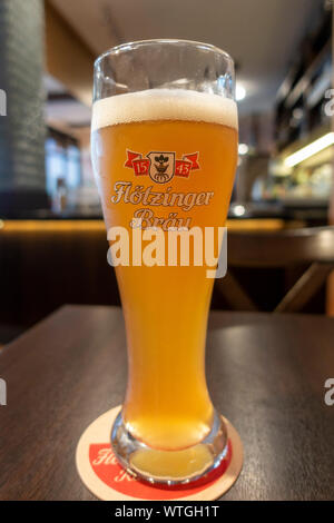 Ein Flötzinger Bräu (Bier) auf einem Tisch im Restaurant und Achterbahn in München, Bayern, Deutschland sitzen. Stockfoto