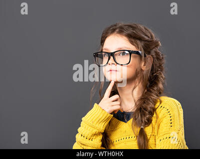 Denken Grimassen ernsthafte Schülerin in Brillen suchen auf Grau studio Hintergrund. Zurück zu Schule. Der Begriff der Bildung. Closeup Portrait Stockfoto