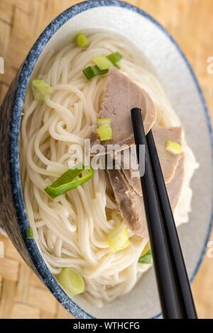 Ein studio Foto von Sticks packte einen Schweinefleisch Schicht auf einer Schüssel Nudeln schneiden. Stockfoto