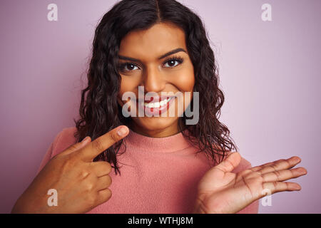 Junge schöne Transsexuelle transgender Frau stehend über isolierte rosa Hintergrund sehr glücklich zeigte mit Hand und Finger Stockfoto