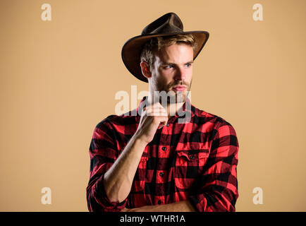 Schöne bärtige Macho. American Cowboy. Schönheit Standard. Beispiel wahrer Männlichkeit. Cowboy Hut tragen. Westliche leben. Mann unrasiert Cowboy beigen Hintergrund. Unrasierten Kerl in Cowboyhut. Stockfoto