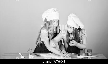 Sie kochen. Adorable kleinen Mädchen genießen zusammen kochen. Kleine Kinder Kochkurs. Niedliche Köche in kochschürzen Gestaltung der Figuren aus Teig mit Schimmel. Stockfoto