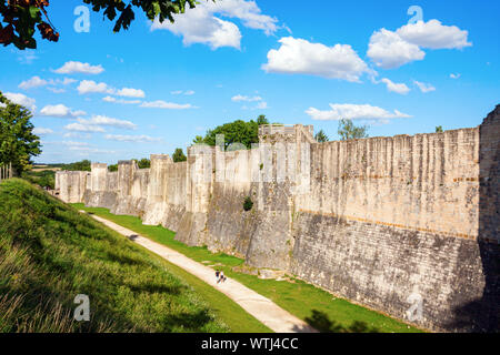 Menschen zu Fuß entlang der mittelalterlichen Stadtmauer mit Türmen und einen tiefen Graben unter einem blauen Himmel mit Wolken verstärkt. Provins, SEINTE-et-Loire, Frankreich. Stockfoto