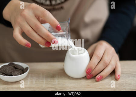 Barista in eine Schürze gießt Milch in eine Tasse. Barista arbeiten in einem Coffee Shop. Stockfoto