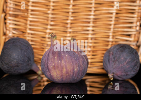 Hinter der Gruppe von vier ganze frische Feigen Früchte mit geflochtenen Rattan Stockfoto