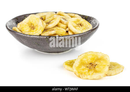 Viele Schichten von süssen gelben trockenen Banane in dunkle Keramik Schüssel auf weißem Hintergrund Stockfoto
