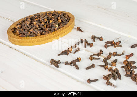 Menge ganz trocken braun Nelke auf Bambus Untersetzer auf weißem Holz Stockfoto