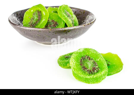 Viele Scheiben süß grün kandierte Kiwis in dunklen Keramik Schüssel auf weißem Hintergrund Stockfoto