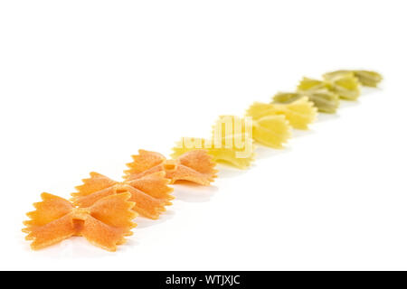 Gruppe von neun Ganze rote, gelbe und grüne ungekocht Farfalle diagonal auf weißem Hintergrund Stockfoto