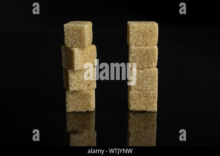 Gruppe der Acht ganze süsse Brown Sugar Cube auf schwarzem Glas isoliert Stockfoto