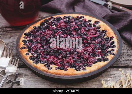 Berry pie mit Kirsche, Johannisbeere, Brombeere, Heidelbeere auf Holztisch im rustikalen Stil. Hausgemachter Käsekuchen. Stockfoto