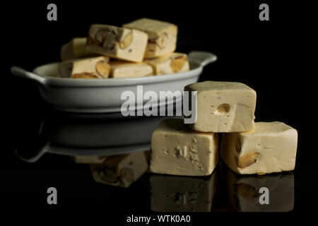 Menge ganz süßen weißen Nougat in weiße, ovale Keramik Schüssel auf schwarzem Glas isoliert Stockfoto