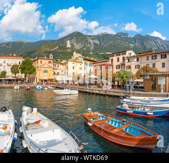 MALCESINE, Italien, 13. Juni 2019: Der kleine Hafen am Ufer des Lago di Garda See mit dem 2000 m hohen Bergen im Hintergrund. Stockfoto