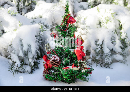 Kochen für Weihnachten und das neue Jahr. Hand machte kleine Weihnachtsbaum mit Spielwaren, Geschenke eingerichtet, Kegel und Bänder in einem verschneiten Wald gemalt. Familie tr Stockfoto