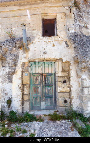 Verfallene hölzerne Türen vorne mit abblätternder Farbe am Eingang zu einem Sassi rock Wohnhöhle in Matera, Basilcata, Süditalien Stockfoto