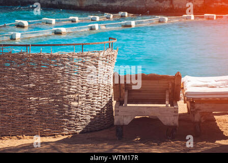 Zwei Holz- leere Liege mit Handtüchern eingewickelt an einem schönen Strand vor einem marine Hintergrund. Stockfoto