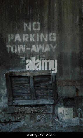 Ein dunkles, grungiges Bild, das eine alte Holzpalette zeigt, die auf ihrem Ende unter der Aufschrift „No Parking Tow-Away Zone“ steht. Stockfoto