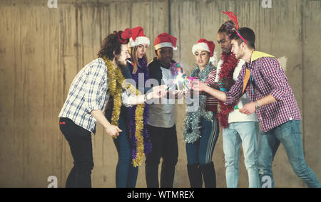 Multiethnische Gruppe junger happy and Business Leute Beleuchtung eine Wunderkerze und Spaß beim Silvester feiern in der betonwand an Stockfoto