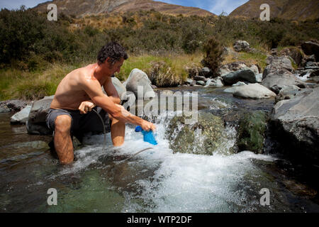 Dallas Hewet immer frisches Wasser aus einem Bach durch Gabeln Hütte, zu den Mavora Hütte, Southland, Neuseeland. Stockfoto