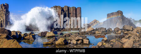 Panorama der Wellen über Basalt Felsformationen erstellen ein Regenbogen über Rock Pools im Bombo Landspitze Steinbruch brechen, New South Wales Coast, Australien Stockfoto