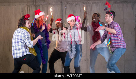 Multiethnische Gruppe junger happy and Business Leute tanzen mit Wunderkerzen und Spaß beim Silvester feiern in der Betonwand Stockfoto