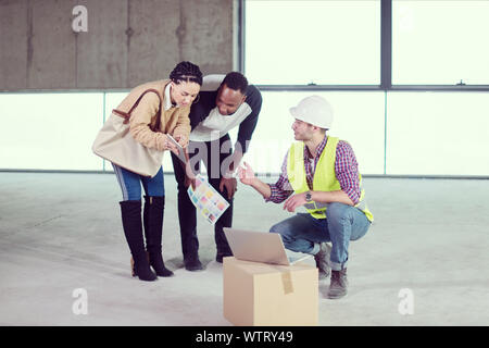 Architekt Ingenieur mit Laptop Computer und zeigt Haus Design plant, eine junge, multiethnische Paar an der Baustelle Stockfoto