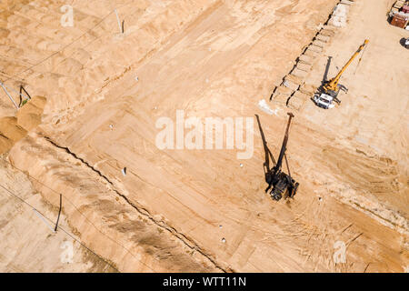 Industrielle gelbe LKW-Kran und Stapel Bohrmaschine im City Baustelle arbeiten. Antenne Top View Stockfoto