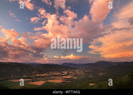 Schönen Sonnenuntergang mit brillanten farbigen Wolken über die Zeilen von Lavendel in der Provence, Frankreich in der Nähe von Valensole. Nach einem Sturm die Wolken rosa gedreht. Stockfoto