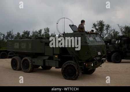 Ein High Mobility Artillery Rocket System mit Batterie Q, 3.Bataillon, 12 Marines, 3rd Marine Division, Erstellt am Strand nach dem Aussteigen einen Landing Craft zu mobilisieren, Utility, in Verbindung mit einer amphibischen Raid durch Kampf Gummi Streifzüge Handwerk aus dem Dock Landung Schiff USS Ashland (LSD 48) mit Kin Blau, Okinawa, Japan, August 16, 2019. Dieser Betrieb einer HIMARS Einfügen von LCU während eines simulierten amphibischen Raid demonstriert naval Expeditionary kombiniert - arme Manöver von Amphibischen Versand über Marine Air-Ground Task Force Fähigkeiten und Kriegsführung Domänen. (U.S. Marine Corps Foto b Stockfoto