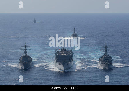Von links nach rechts, die Geführte-missile Destroyer, USS Forrest Sherman (DDG98), die schnelle Bekämpfung support ship USNS (T-AOE6), und die geführten Anti-raketen-Zerstörer USS Schwer (DDG107) Durchführung einer Tanken - auf See, während der geführten-missile Cruiser USS Normandie (CG60) (ganz links) und geführte-missile Destroyer USS Winston S. Churchill (DDG81) (Mitte rechts) Stand-by im Atlantischen Ozean, Sept. 7, 2019. Die Forrest Sherman, Lieferung, Ernst, Winston S. Churchill, und in der Normandie sind im Gange, um nach einem Ausfall wegen Hurricane Dorian Anfang dieser Woche. Commander, Marine Region Mid-Atlantic bestellt Alle Stockfoto