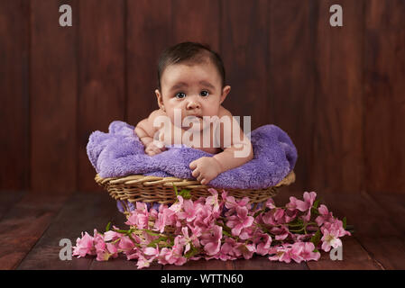 Cute Baby schauen in die Kamera auf dunklen Studio Holz- Hintergrund Stockfoto