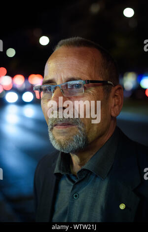 Berlin, Deutschland. 04 Sep, 2019. Peter-Christian Bürger, Zeitzeuge und Mitglied der Bundesstiftung Aufarbeitung der SED-Diktatur, Spaziergänge durch eine Straße im Berliner Bezirk Friedrichshain nach einem Arbeitstag im Licht einer Straßenlaterne. Sein Gesicht leuchtet durch eine Leuchtreklame. (Dpa-Geschichte: 30 Jahre Prager Botschaft) Credit: Gregor Fischer/dpa/Alamy leben Nachrichten Stockfoto