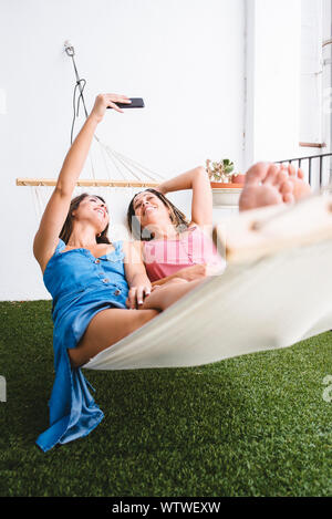 Zwei barfuß Frauen liegen auf Hängematte unter einem selfie. Stockfoto