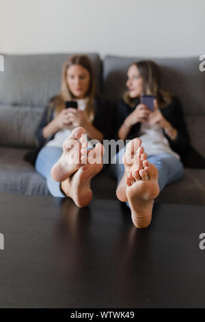 Mädchen in eine Couch mit Füßen auf einem Tisch Stockfoto