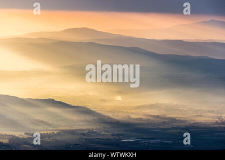 Sonnenstrahlen kommen über ein Tal in Umbrien (Italien) mit schönen goldenen Stunden Farben. Stockfoto