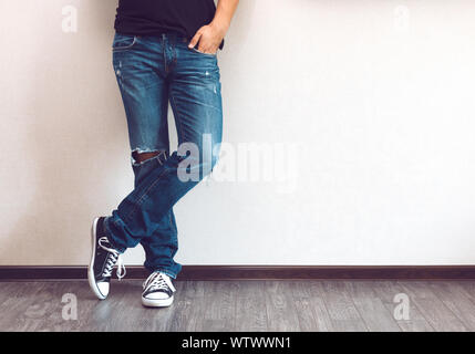 Die Beine Junge Mode Mann in Jeans und Sneakers auf Holzboden Stockfoto