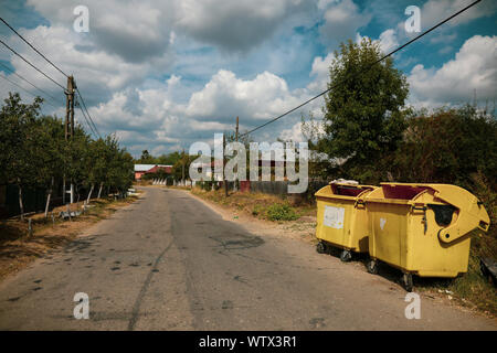 Gelb Kunststoff Müllcontainer auf einem Dorf Straße mit niemand um in ländlichen Rumänien Stockfoto