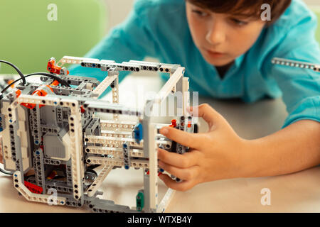 Ernsthafte Schüler arbeiten auf seinem komplizierten Roboter. Stockfoto