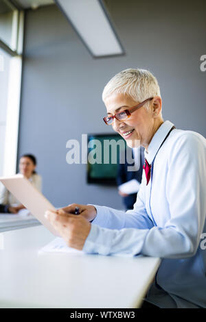 Lächelnd reife Geschäftsfrau im modernen Büro arbeiten Stockfoto