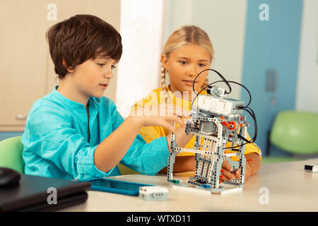 Junge erklärt seine Klassenkameradin Prinzipien der Arbeit seines Projekts. Stockfoto