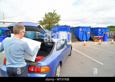 Mann, die Schrott aus dem Kofferraum für Recycling auf Rat hosehold Recycling center in England Stockfoto