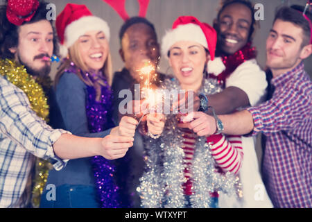 Multiethnische Gruppe junger happy and Business Leute Beleuchtung eine Wunderkerze und Spaß beim Silvester feiern in der betonwand an Stockfoto