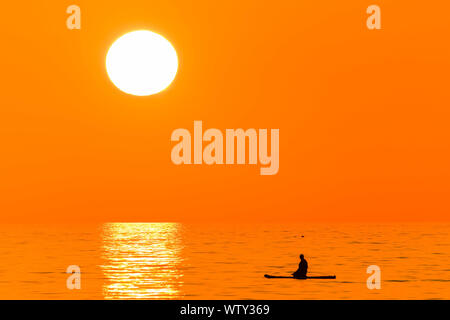 Aberystwyth Wales UK Mittwoch, den 27. März 2019 Deutschland Wetter: ein Sonnenuntergang, am Ende einer anderen Tag der warmen Frühlingssonne, Silhouetten einer Person paddleboarding auf te Wohnung ruhige See in Aberystwyth, auf der Cardigan Bay Küste von West Wales. Hoher Druck weiterhin das Wetter für viel der UK zu dominieren, mit sesshaften Bedingungen und klare fast wolkenlosen blauen Himmel Foto Keith Morris/Alamy leben Nachrichten Stockfoto