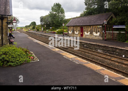 Der Bahnhof Horton-in-Ribblesdale, North Yorkshire an trüben, bewölkter Tag, mit einem Diesel Personenzug in Richtung Norden nähert sich in der Ferne Stockfoto