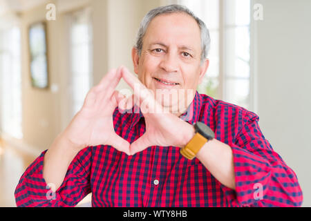 In der Nähe von attraktiven älteren Mann zu Hause in der Liebe mit Herz und mit Hand lächelnd. Romantische Konzept. Stockfoto