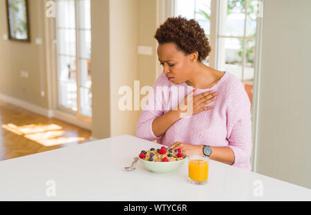 Junge afrikanische amerikanische Frau, die gesundes Frühstück am Morgen zu Hause Unwohlsein und als Symptom für kalte oder Bronchitis Husten. Gesundheitswesen Stockfoto