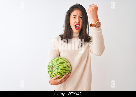 Junge schöne chinesische Frau mit Wassermelone stehend über isoliert weißer Hintergrund genervt und frustriert schrie mit Zorn, verrückt und schreien Stockfoto